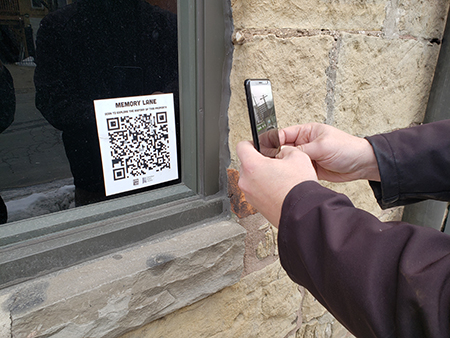 Person hlding a phone taking photo of QR code on a window