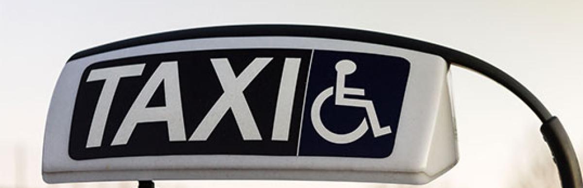 Taxi sign showing vehicle is equipped for assistance and transportation for handicapped person with text "Taxi Scrip"