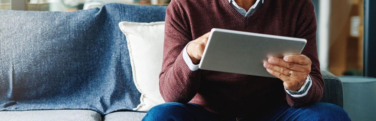 Cropped shot of a mature man using his digital tablet while relaxing at home.