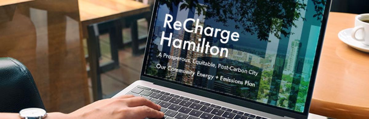Person reading ReCharge Hamilton on laptop at cafe