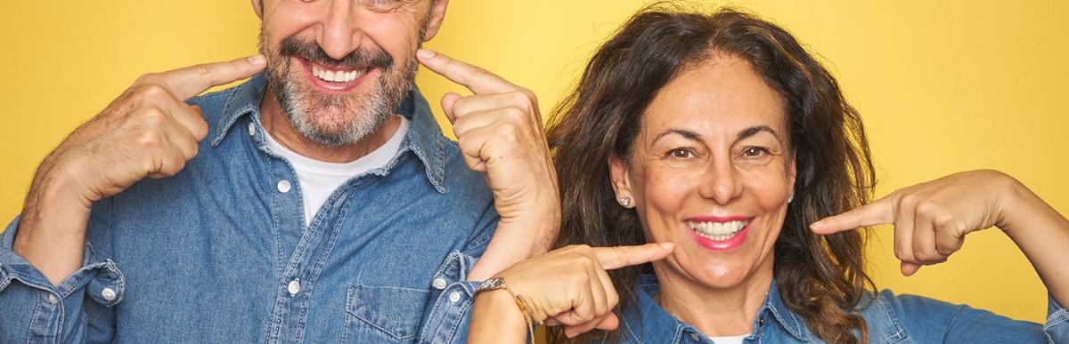 Middle age couple smiling cheerful showing and pointing with fingers teeth and mouth. Dental health concept.