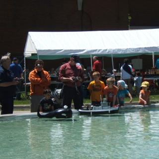 people playing with remote control boats in a pool